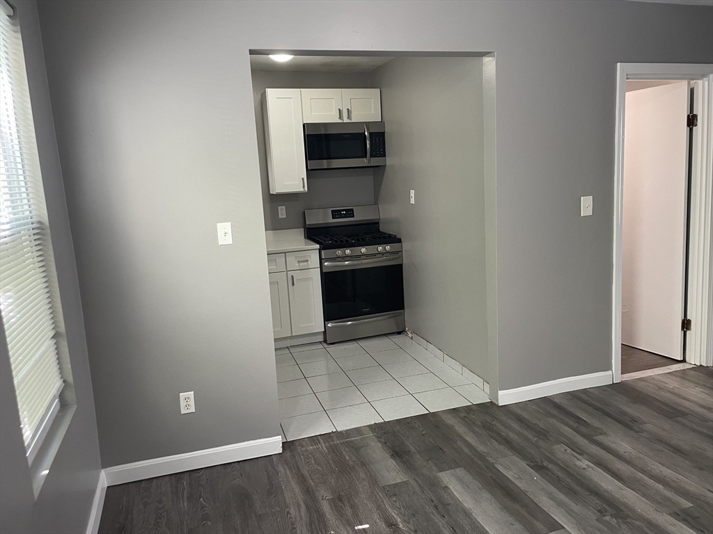 8 Cheever Court, Unit 1 Boston, MA 02128 - Photo 10 of 16 an empty room with wooden floor kitchen view and windows