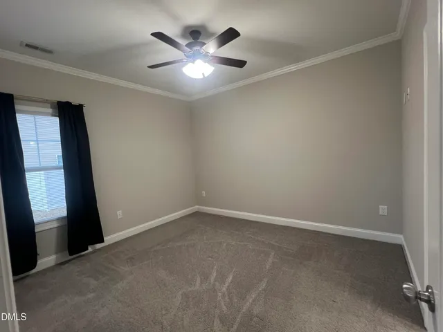 an empty room with a chandelier fan and windows