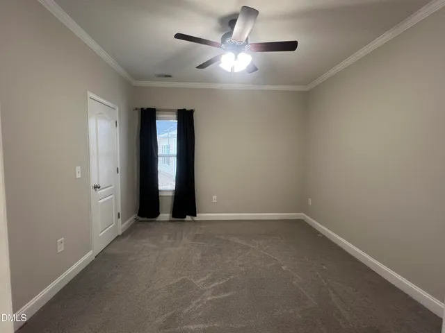 an empty room with chandelier fan and windows