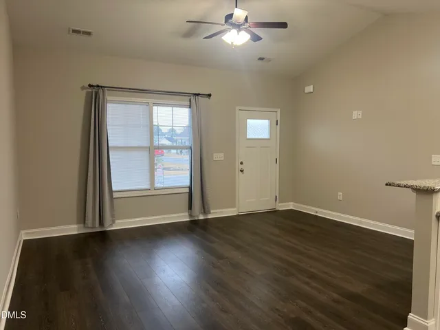 an empty room with wooden floor fan and windows