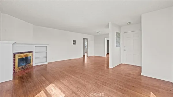 a view of empty room with wooden floor and fireplace