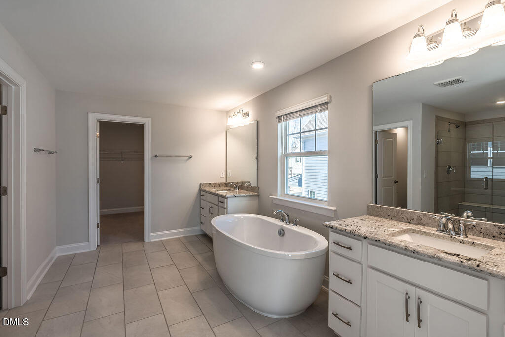 717 Ressler Street Holly Springs, NC 27540 - Photo 18 of 32 a bathroom with a granite countertop sink mirror and bathtub