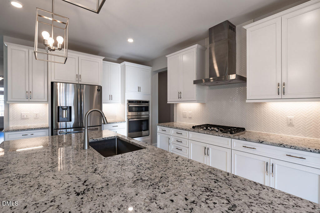 717 Ressler Street Holly Springs, NC 27540 - Photo 7 of 32 a kitchen with stainless steel appliances granite countertop a sink a stove a refrigerator and cabinets