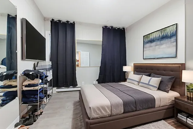 a bedroom with a bed and a flat tv screen on the dresser