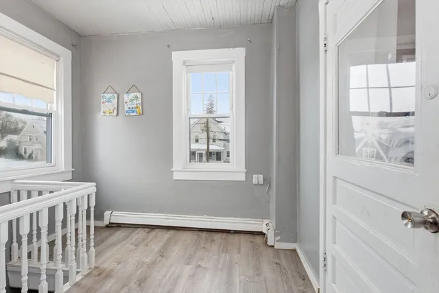 a view of an empty room with a window and wooden floor