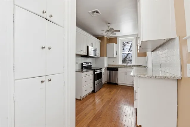 a kitchen with stainless steel appliances a refrigerator a sink and white cabinets