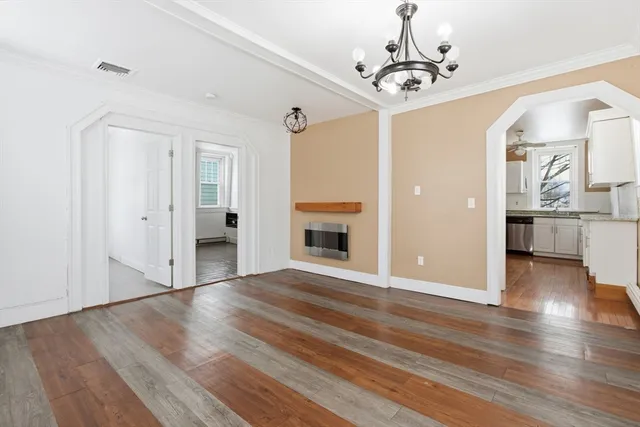 a view of a livingroom with wooden floor a kitchen space with a sink and refrigerator