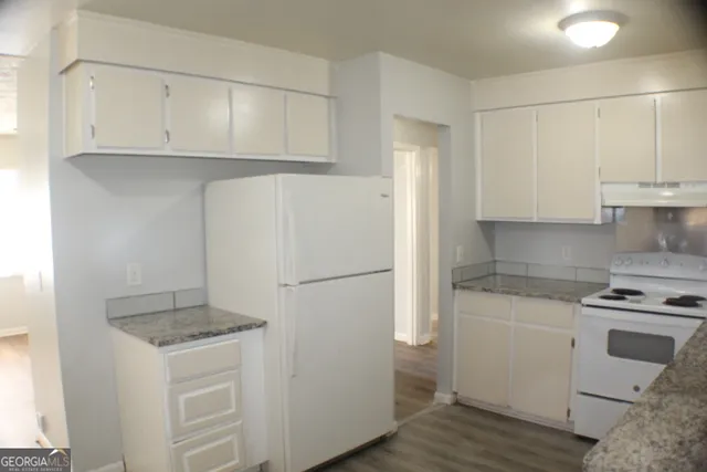 a kitchen with granite countertop white cabinets and white appliances