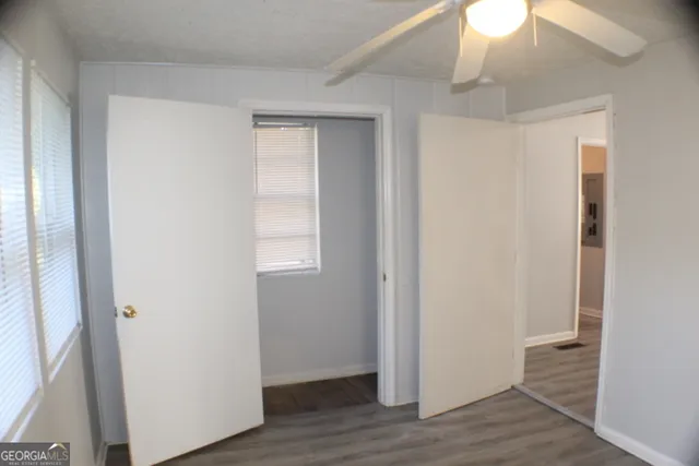 a view of an empty room with wooden floor and a window