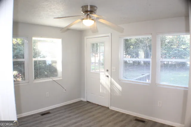 a view of an empty room with wooden floor and a window