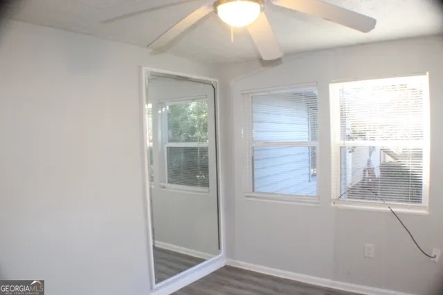 an empty room with wooden floor fan and a window