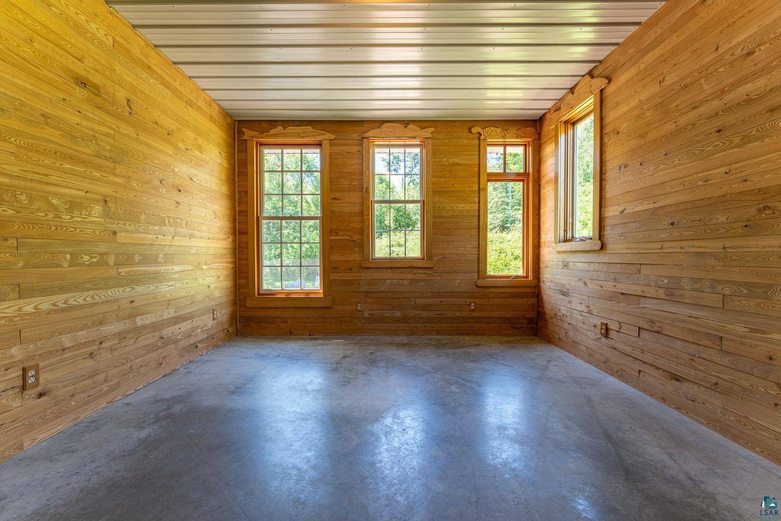 9734 Alango Road Angora, MN 55703 - Photo 12 of 41 Room featuring natural wood plank walls, concrete flooring, and a corrugated metal ceiling