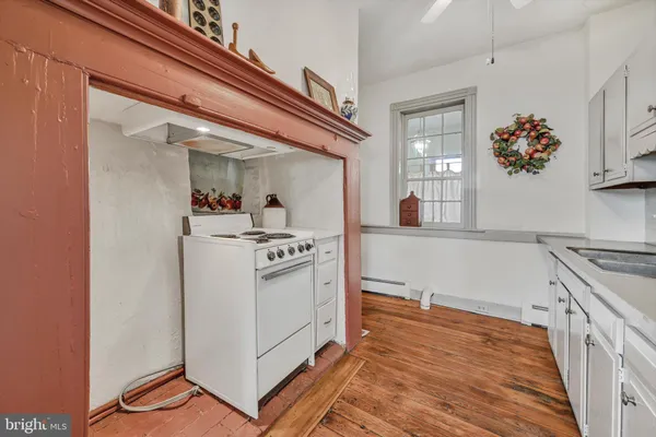 a kitchen with stainless steel appliances granite countertop a sink dishwasher stove and white cabinets with wooden floor