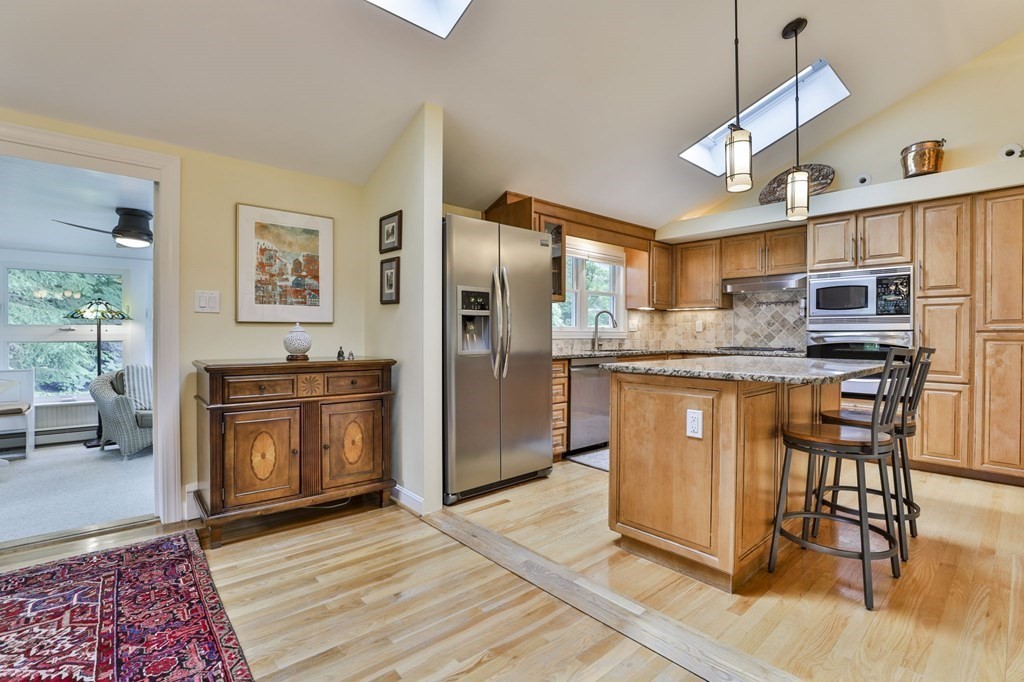 75 Valley Road Milton, MA 02186 - Photo 13 of 41 a kitchen with stainless steel appliances granite countertop a refrigerator a stove a sink a dining table and chairs with wooden floor