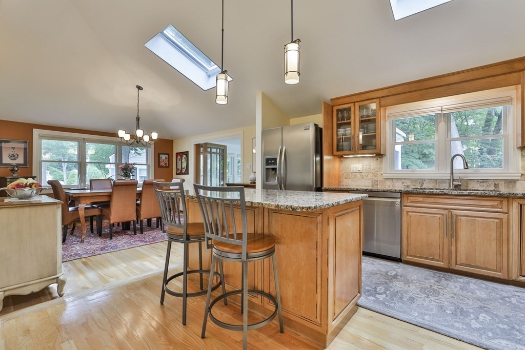 75 Valley Road Milton, MA 02186 - Photo 7 of 41 a open kitchen with stainless steel appliances granite countertop a stove top oven a sink dishwasher a dining table and chairs with wooden floor