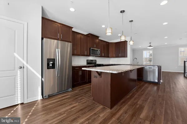 a large kitchen with a center island wooden floor stainless steel appliances and a window
