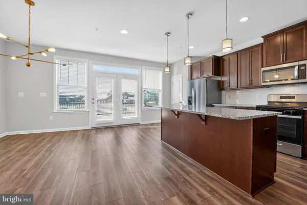 a kitchen with stainless steel appliances granite countertop a refrigerator a oven a sink dishwasher and a stove with wooden floor