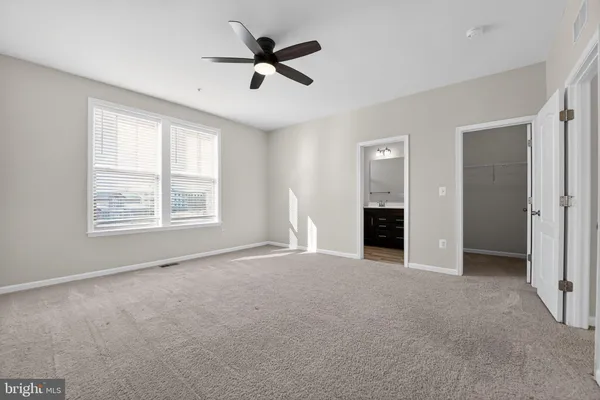 an empty room with windows and ceiling fan