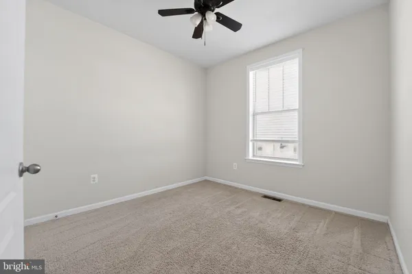an empty room with a window and a ceiling fan