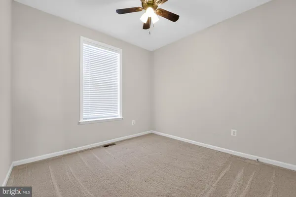 an empty room with a window and a chandelier fan
