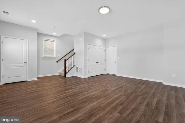 a view of an empty room with wooden floor and stairs