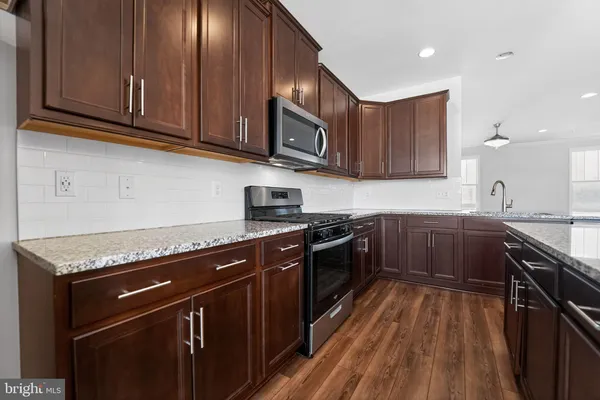 a kitchen with stainless steel appliances granite countertop wooden cabinets stove top oven and sink