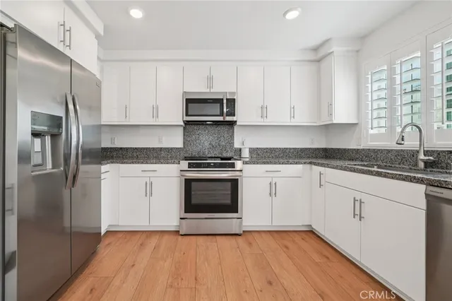 a kitchen with granite countertop white cabinets stainless steel appliances and a refrigerator