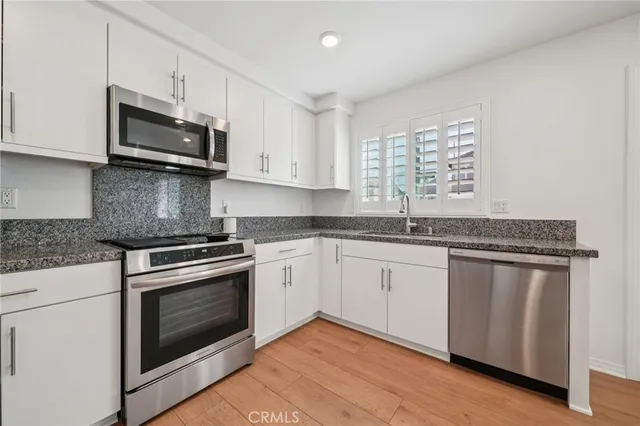 a kitchen with granite countertop white cabinets stainless steel appliances and a sink