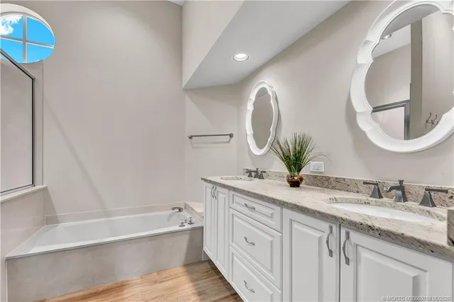 a bathroom with a granite countertop sink mirror and bathtub