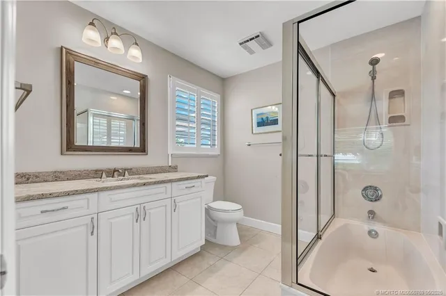 a bathroom with a granite countertop sink a toilet a mirror and shower