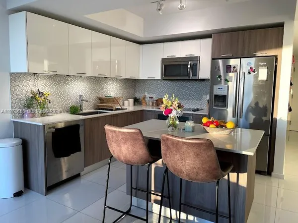 a kitchen with stainless steel appliances kitchen island granite countertop a dining table and chairs