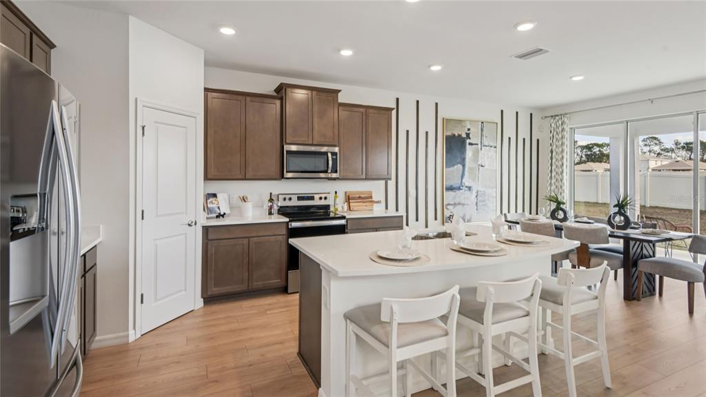 11238 Duckling Way Weeki Wachee, FL 34613 - Photo 3 of 30 a kitchen with stainless steel appliances kitchen island granite countertop a refrigerator a stove a sink a dining table and chairs