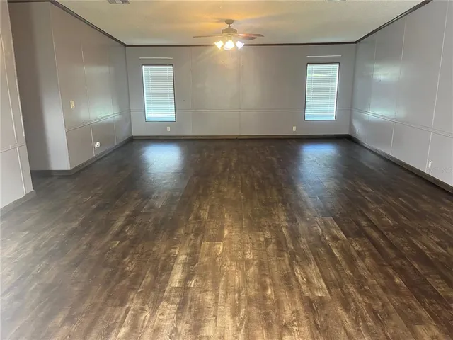 an empty room with wooden floor and windows