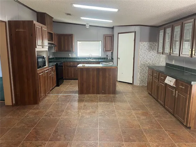 a large kitchen with granite countertop a stove a refrigerator and a sink