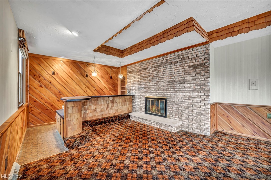 230 Crosse Road Amherst, OH 44001 - Photo 34 of 47 Carpeted living room featuring wooden walls, a brick fireplace, and brick wall