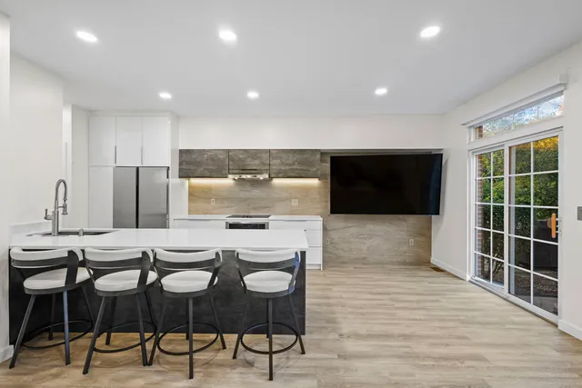 a kitchen with stainless steel appliances kitchen island granite countertop a stove a refrigerator and a dining table with wooden floor