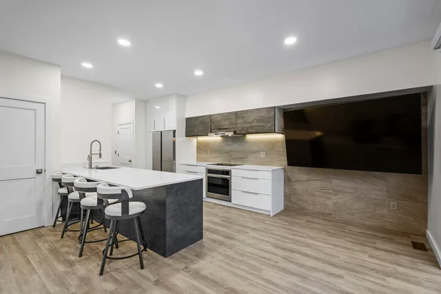 a kitchen with stainless steel appliances kitchen island granite countertop a table chairs sink and cabinets