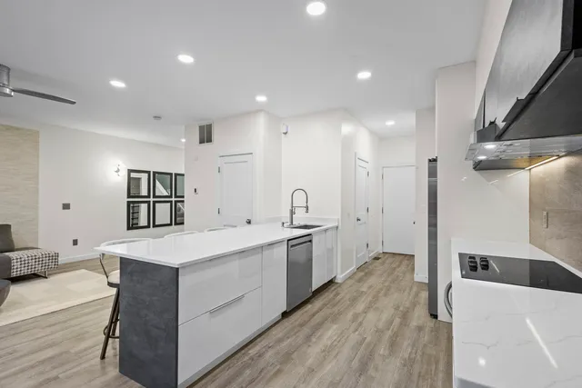 a large white kitchen with wooden floor and a sink