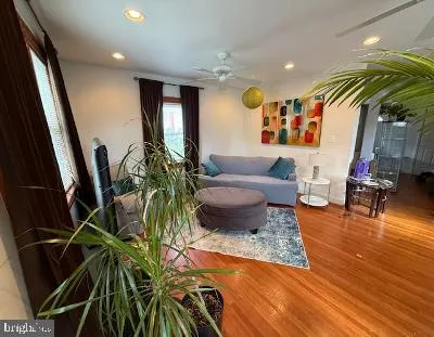 a living room with patio furniture and potted plants with wooden floor