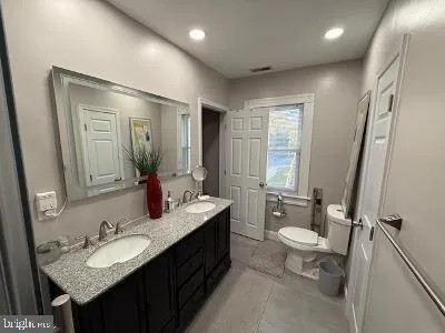 a bathroom with a granite countertop sink toilet a mirror and a tub