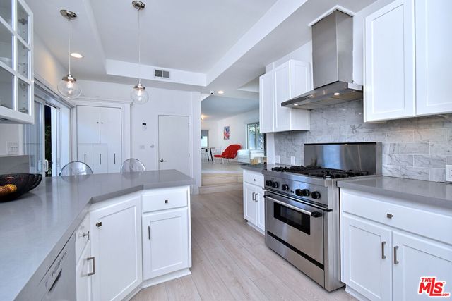 a kitchen with stainless steel appliances granite countertop a stove a sink and a white wooden cabinets