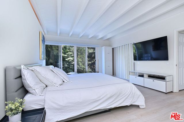 a bedroom with a bed television and a large window