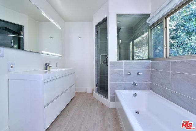 a bathroom with a bathtub a sink a mirror a vanity and a shower