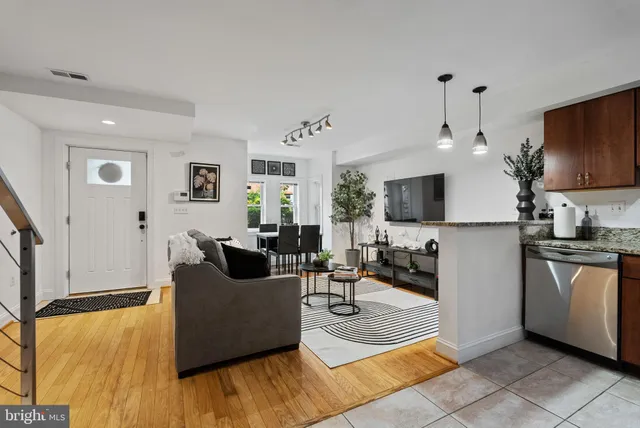 a living room with stainless steel appliances furniture a flat screen tv and a refrigerator