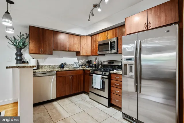 a kitchen with stainless steel appliances granite countertop a refrigerator a stove a sink and a microwave