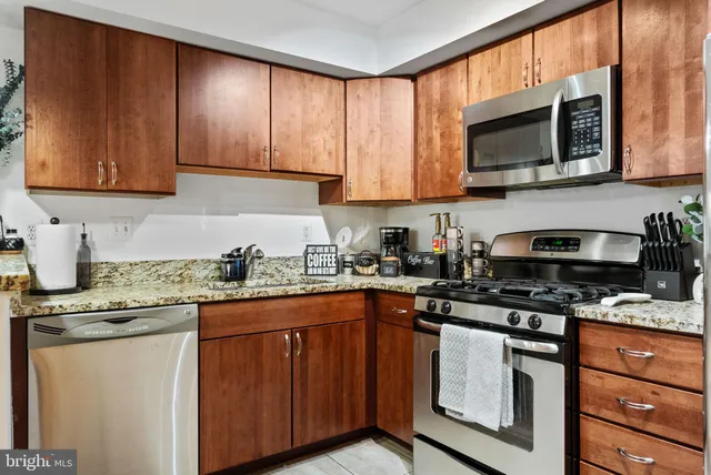a kitchen with stainless steel appliances granite countertop wooden cabinets a stove top oven a sink and dishwasher