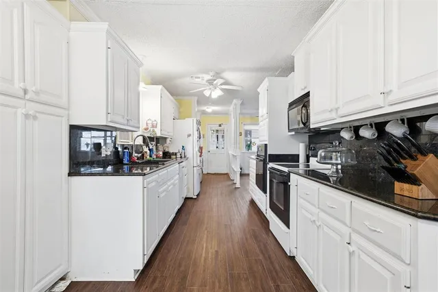 a kitchen with stainless steel appliances a stove top oven a refrigerator a sink dishwasher and white cabinets with wooden floor