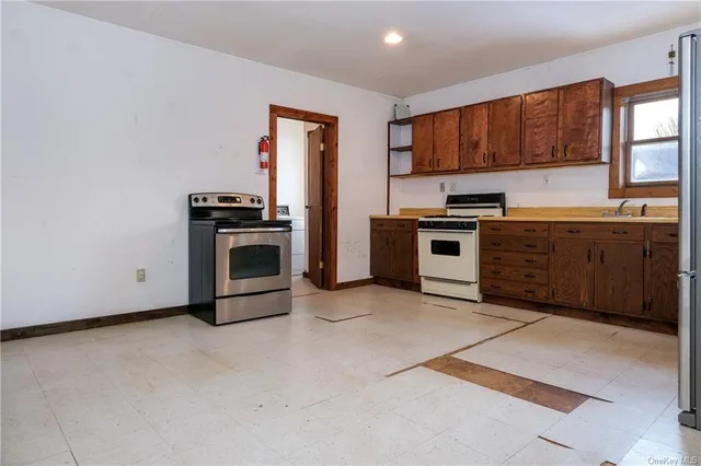 a view of a refrigerator in kitchen and an empty room