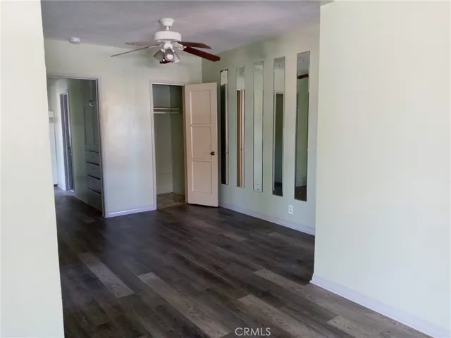 a view of a hallway with wooden floor and a ceiling fan