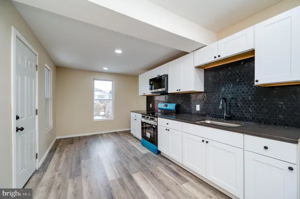 a kitchen with granite countertop a stove top oven a sink a counter space and cabinets